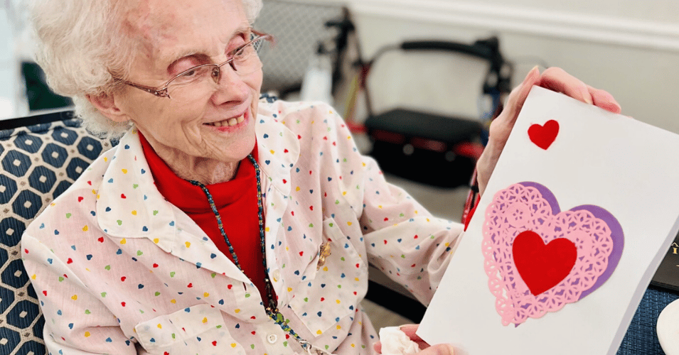 A Pacifica Senior Living resident shows off her heart shaped craft